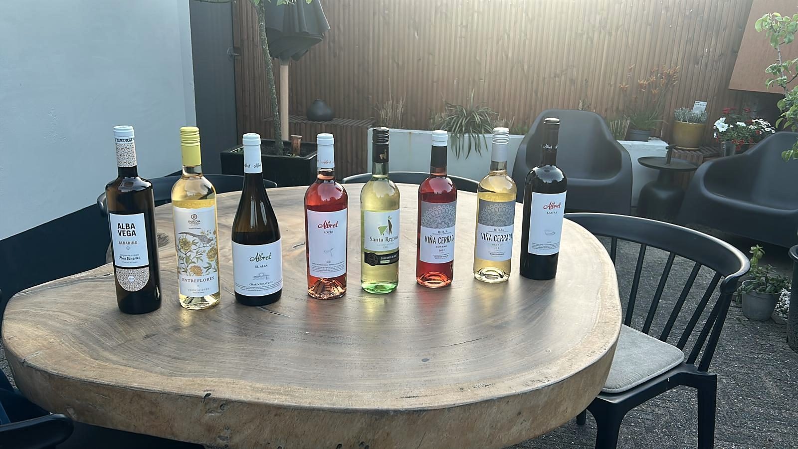 Een rij flessen uit het assortiment op een houten tafel