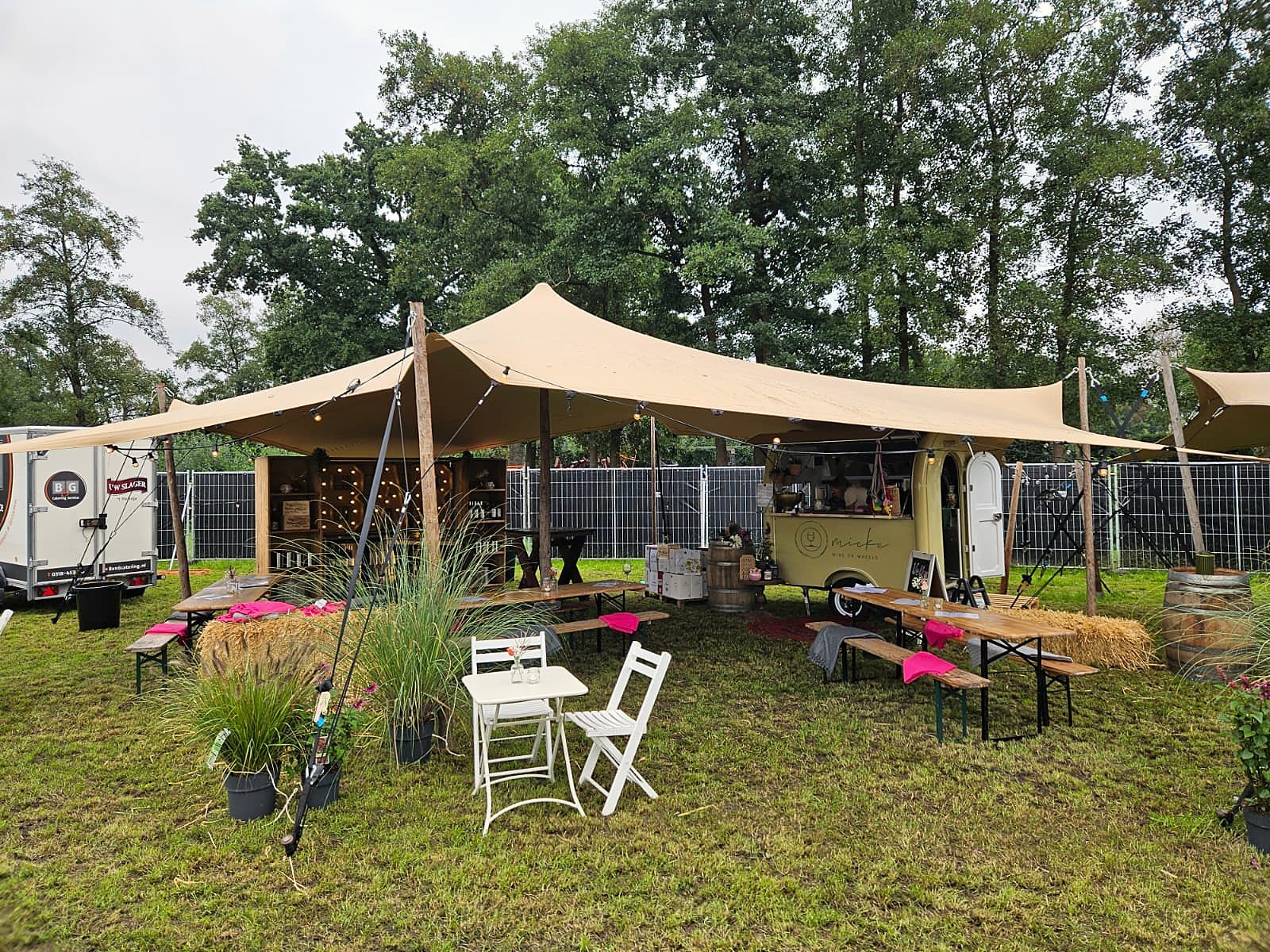 De stand van buiten: een stretchtent met de bar, de wijnkar en bankjes op het gras